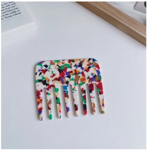 Macro detail of wide-tooth acetate hair comb with colorful marble terrazzo patterns