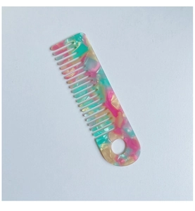 Detail of wide-tooth comb showing rainbow marble acetate texture and hanging hole design