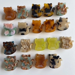 Detailed macro view of cat-shaped acetate hair claws in various colorful marble patterns
