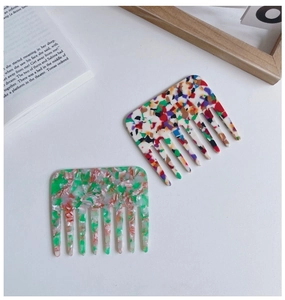Detail of two wide-tooth acetate hair combs with colorful marble and mosaic patterns