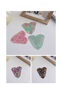 Detailed macro view of heart-shaped acetate hair combs in various pastel patterns
