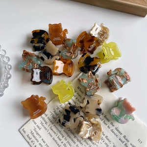 Mini cat-shaped acetate hair claws in various colors displayed on a white table