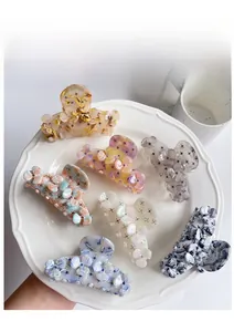 Detail of floral acetate hair claws in assorted colors displayed on a white plate