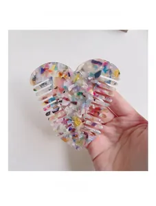 Macro shot of a colorful acetate heart comb held by hand to show texture and size