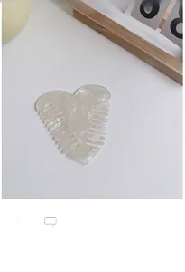 Close-up of heart-shaped cellulose acetate hair comb with pearlescent marble texture