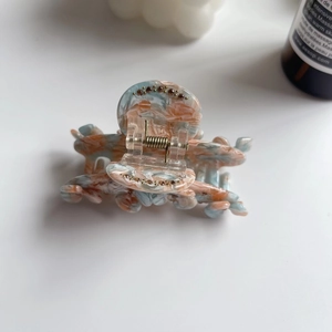 Detail of marble pattern acetate hair claw clip with sparkling rhinestones and metal spring