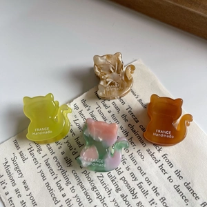 Detail of mini acetate cat hair claws in four colors on a vintage book page