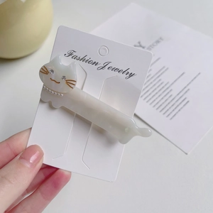 Close-up of cat-shaped acetate hair clip with pearl necklace and rhinestone eye detail