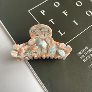 Detail of acetate flower hair claw clip with rhinestones on marble pattern finish