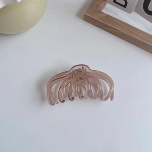 Detailed view of pink translucent hair claw clip with octopus-like teeth on white background