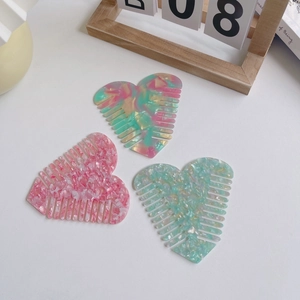 Three heart-shaped acetate hair combs with marble patterns on a clean minimalist background