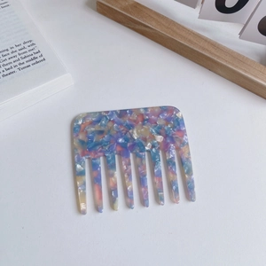 Chic acetate wide-tooth hair comb with multicolor marble pattern on a minimalist desk