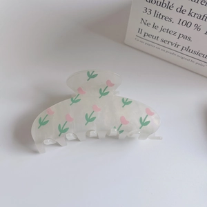 Detail of a large cream floral hair claw clip with pink tulips and green leaves