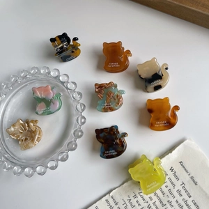 Collection of nine colorful acetate cat-shaped hair claws in various vintage patterns