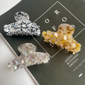Three acetate hair claws with rhinestones in marble, wave, and pearl white textures