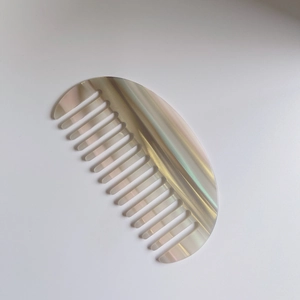Vue détaillée d'un peigne à dents larges en acétate nacré de forme demi-lune