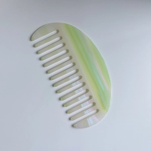 Vue détaillée d'un peigne à dents larges en acétate marbré vert avec fini nacré