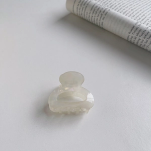 Detailed view of a small cream pearl acetate hair claw clip on a minimal background