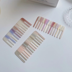 Trois peignes à dents larges en acétate avec dégradé marbré sur un bureau blanc