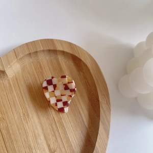Détail d'une pince à cheveux en acétate en forme de cœur avec un motif à carreaux rouge