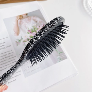 Black and white leopard print air cushion massage hairbrush on a white magazine background