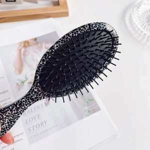 Leopard print air cushion hairbrush with anti-static bristles on a stylish lifestyle background