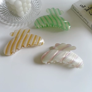 Three colorful acetate hair claws in green orange and pink with striped texture