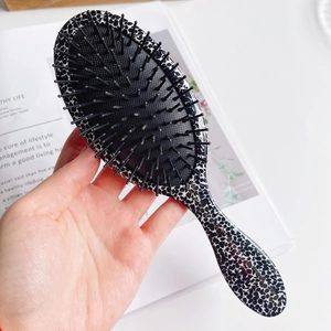 Detail of leopard print paddle brush featuring anti-static bristles and ergonomic handle