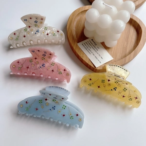 Close-up of four colorful acetic acid hair claws with sparkling multi-color rhinestones