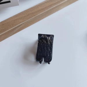 Detail view of mini marble pattern claw clip in black acetate for high ponytail styling