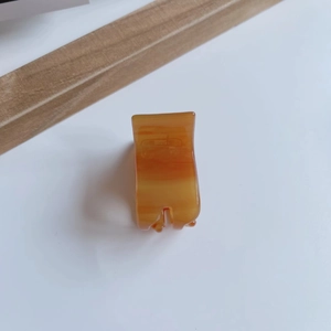 Detailed view of a small amber acetate hair claw clip with marble texture on white surface
