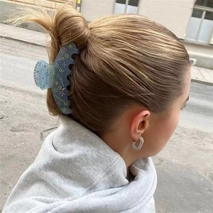 Detail of blue acetate hair claw with floral crystal accents on model in street setting