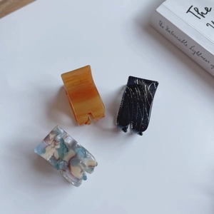 Minimalist acetate hair claw clips set in marble amber, black, and blue patterns