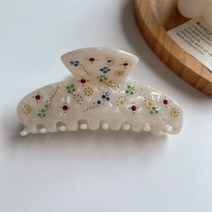 Macro view of acetate hair claw with colorful rhinestones and marble texture on white background