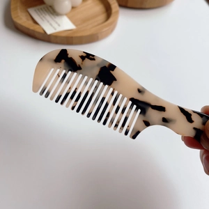 Détail d'un peigne en acétate écaille de tortue avec texture marbrée et poignée ergonomique
