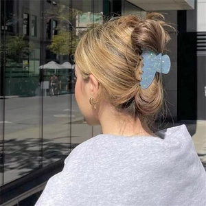 Blue glitter hair claw clip with colorful sequins worn by a model in a modern urban setting