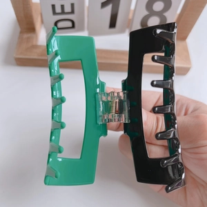 Detail of a large emerald green and black acetate claw clip with a glossy finish