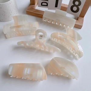 Detail of elegant pearl orange acetate hair claws with marble texture on white surface