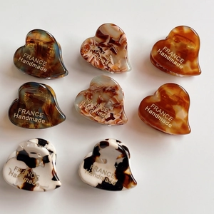 Macro detail of eight heart-shaped acetate hair claws with various marble and tortoiseshell patterns