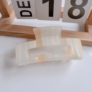 Macro detail of cream white square hair claw clip with elegant pearlescent texture finish