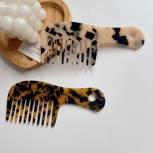 Detail of tortoiseshell and floral acetate wide tooth combs on a wooden heart tray