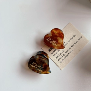 Detailed macro view of two heart-shaped acetate hair claws with premium tortoise textures