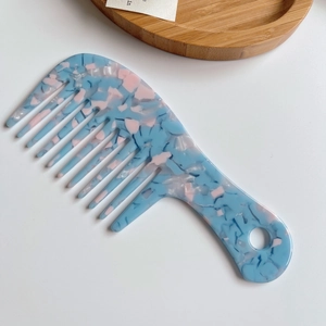 Macro view of wide-tooth acetate comb with blue and pink tortoise shell marble pattern