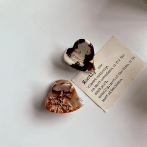 Mini heart-shaped acetate hair claw clips with tortoiseshell pattern and gold label