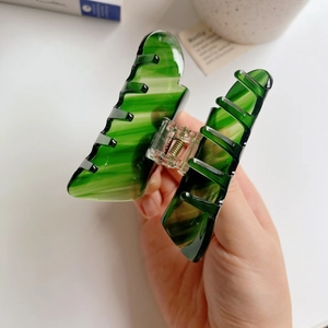 Close-up of deep green acetate hair claw clip with elegant marble ripple patterns