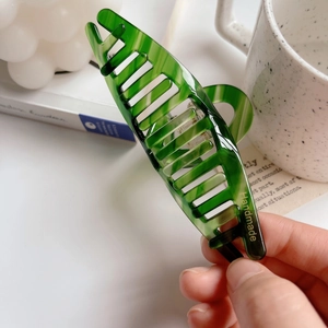Detail of green marbled acetate hair claw with gold Handmade lettering and smooth edges