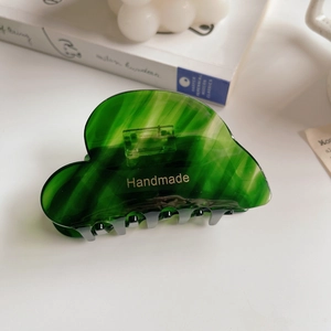 Close-up of emerald green marble acetate hair claw with gold handmade lettering
