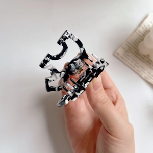 Detail of marble pattern acetate hair claw clip showing smooth texture and metal spring