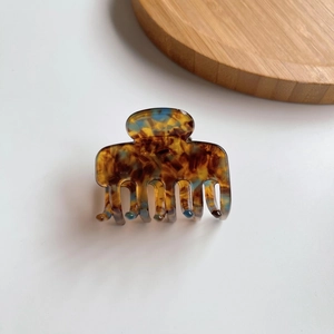 Dettaglio del fermaglio per capelli in acetato tartarugato e blu su vassoio