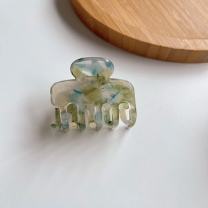 Dettaglio della molletta per capelli in acetato marmorizzato blu e verde con denti forti